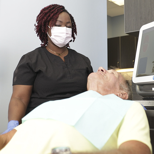 Senior dental patient talking to a dental team member