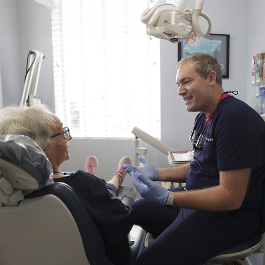 Smiling dentist chatting with a senior patient