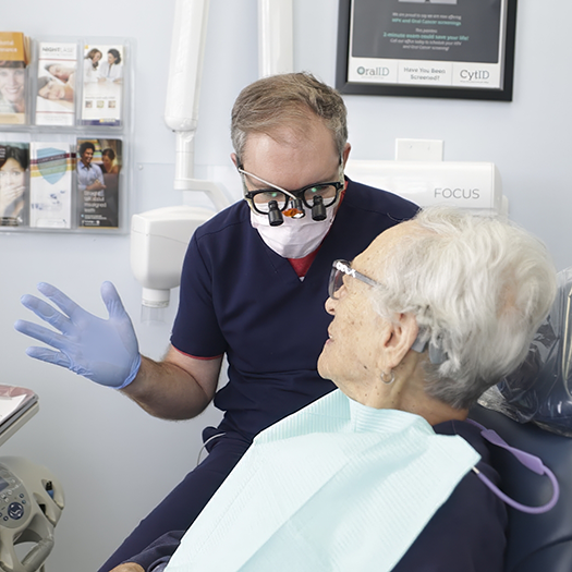 Dentist talking to a senior patient in the treatment chair