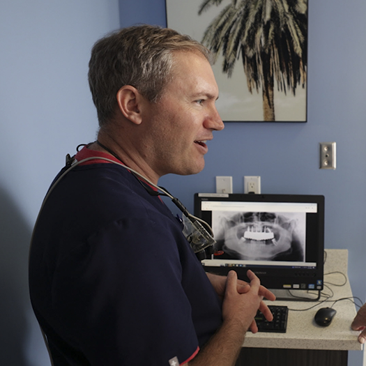 Dentist sitting next to a computer showing x rays of teeth