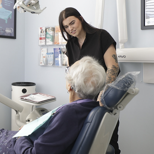 Senior woman in dental chair talking to a dental team member