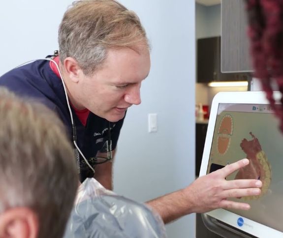 Dentist looking at a screen showing digital models of teeth