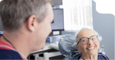 Senior woman in dental chair grinning at her dentist