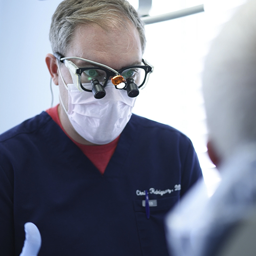 Dentist wearing dental binoculars while talking to a patient